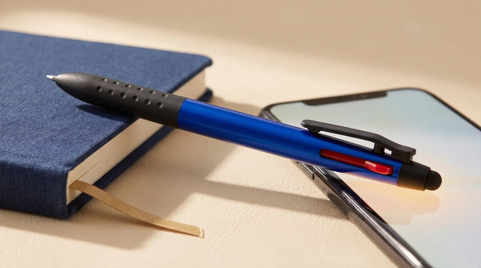 Caneta 3 em 1 touch sobre caderno navy com ponteira encostando no smartphone