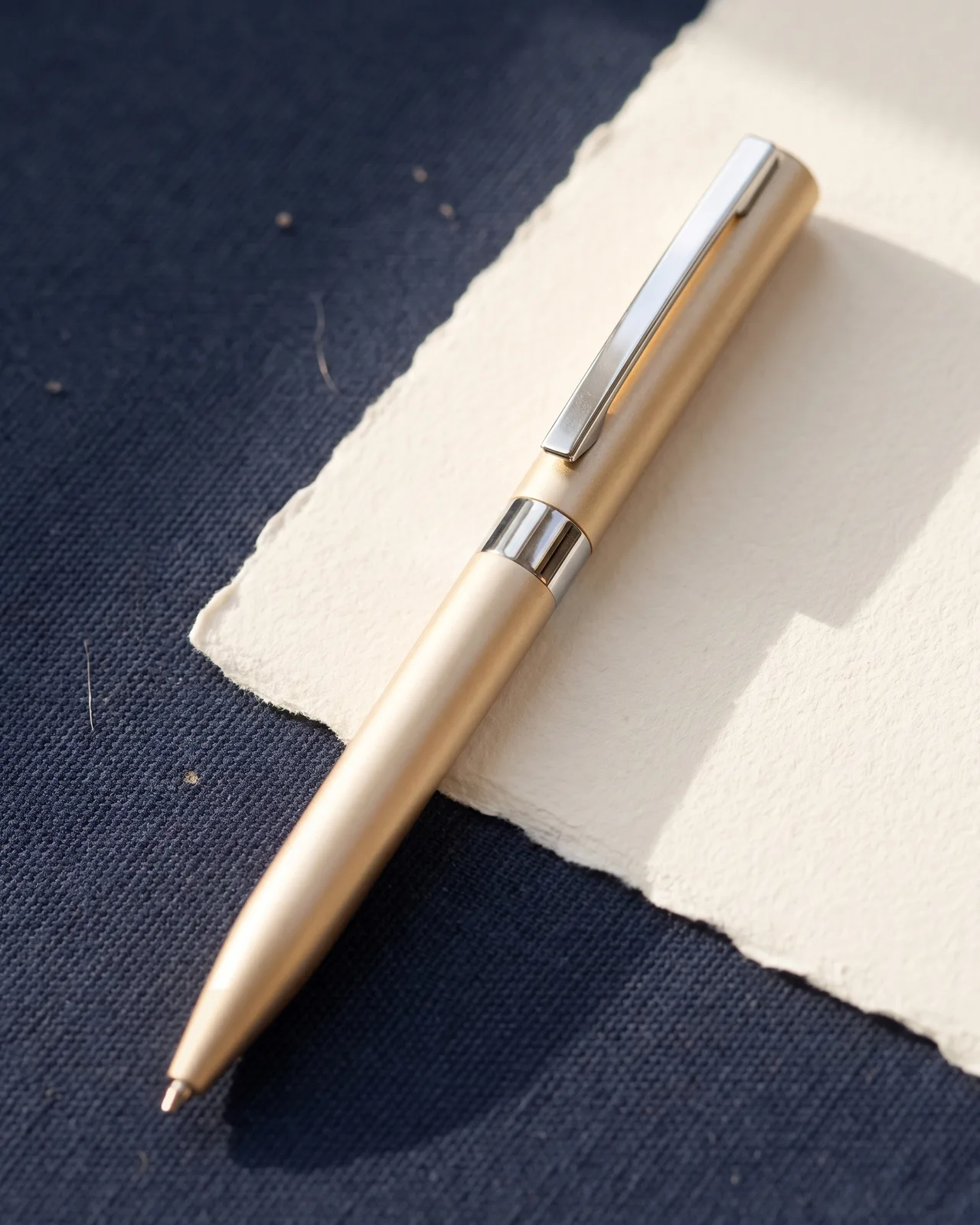 Caneta executiva champanhe sobre folha de papel de algodão e lona navy